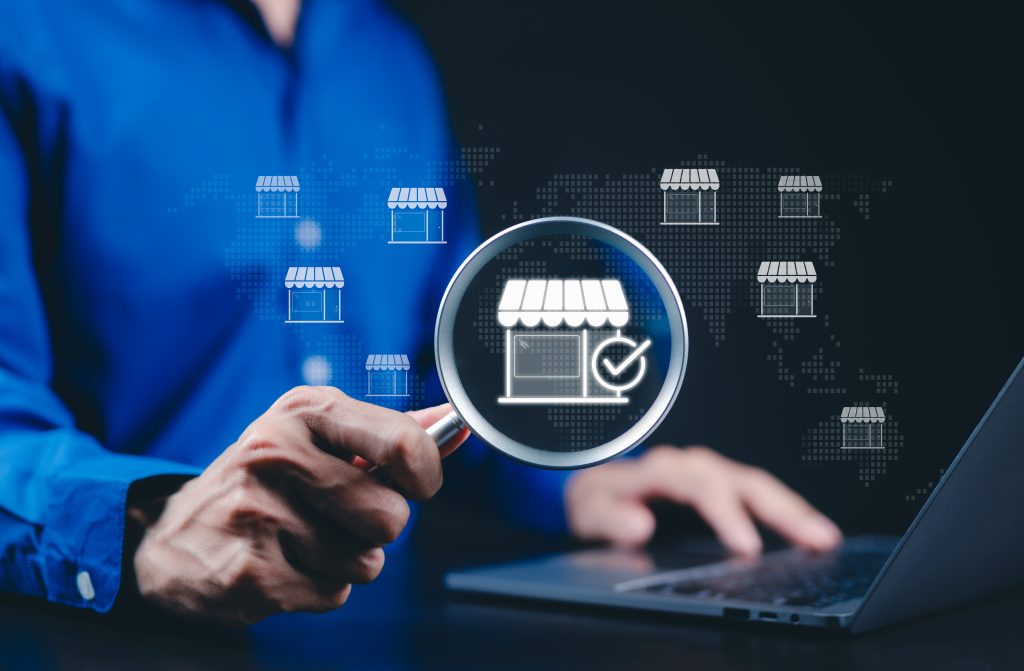 Local marketplace and e-commerce business concept. A person using a laptop with a magnifying glass focusing on a digital storefront, online marketplace, business growth, and e-commerce opportunities.